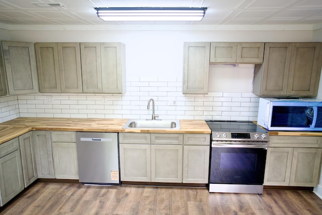 kitchen with decorative backsplash, a sink, an ornate ceiling, stainless steel appliances, and butcher block countertops