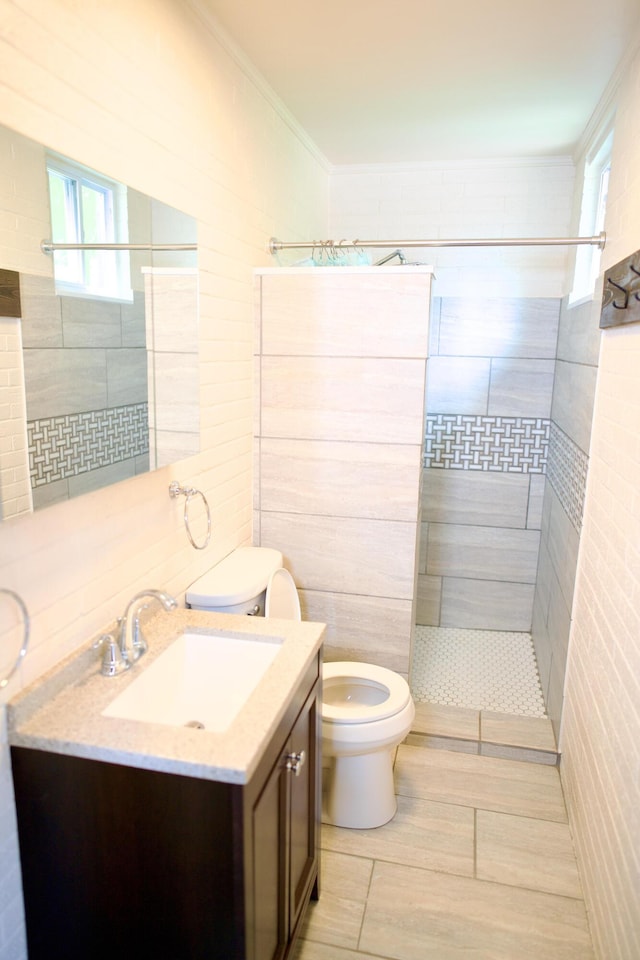bathroom featuring a healthy amount of sunlight, vanity, toilet, and tiled shower