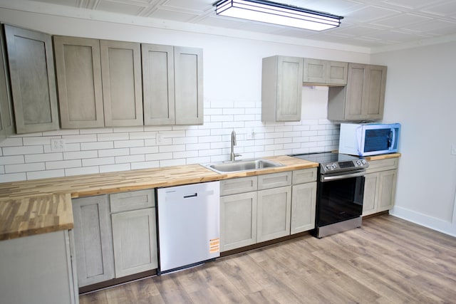 kitchen with electric range, a sink, white microwave, dishwashing machine, and butcher block countertops