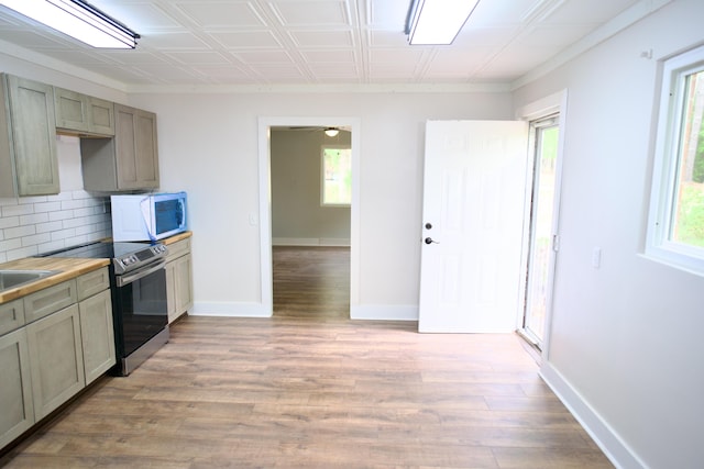kitchen with light wood-type flooring, white microwave, decorative backsplash, and electric stove