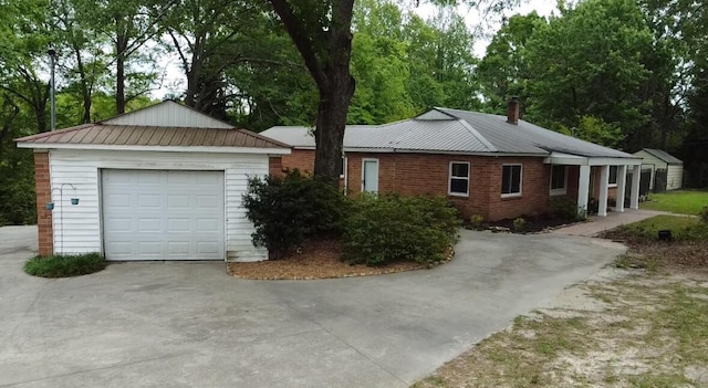 view of front of house with a detached garage, concrete driveway, an outdoor structure, and a chimney