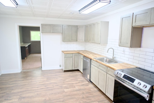 kitchen featuring a sink, appliances with stainless steel finishes, backsplash, and wooden counters