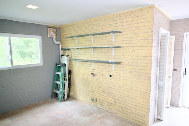 laundry room with brick wall