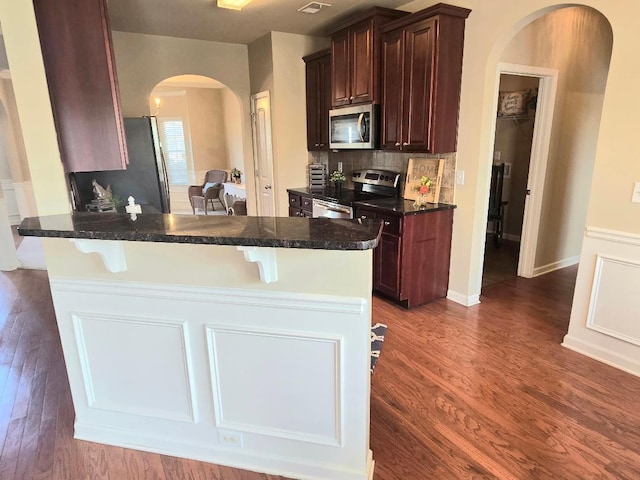 2144 Willhaven Dr, Augusta, GA 30909 - kitchen with stainless steel appliances, arched walkways, a breakfast bar, dark wood-type flooring, and a peninsula