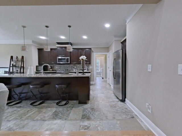 kitchen featuring light stone countertops, appliances with stainless steel finishes, dark brown cabinets, crown molding, and pendant lighting