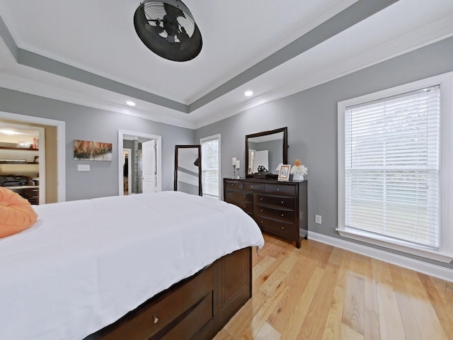 bedroom with a tray ceiling, light wood-type flooring, and ornamental molding