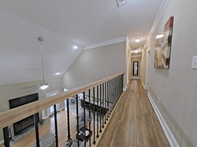 hall featuring crown molding, light hardwood / wood-style floors, and vaulted ceiling