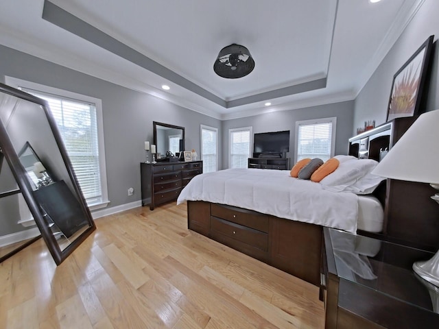 bedroom featuring a raised ceiling, multiple windows, crown molding, and light hardwood / wood-style floors