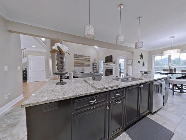 kitchen with a center island with sink, sink, stainless steel dishwasher, and hanging light fixtures