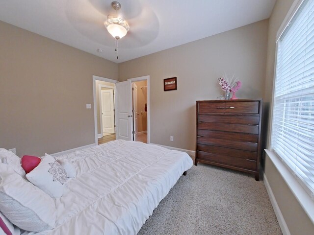 bedroom with multiple windows, ceiling fan, and light carpet