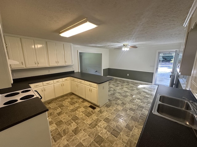 kitchen featuring white cabinets, a textured ceiling, kitchen peninsula, and sink