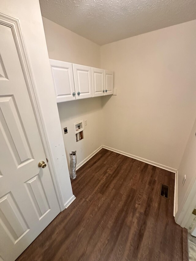 laundry area featuring cabinets, hookup for an electric dryer, dark hardwood / wood-style floors, hookup for a washing machine, and a textured ceiling