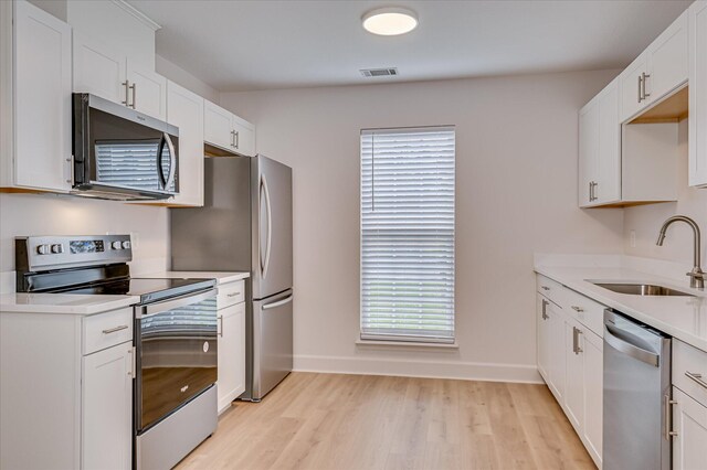 4002 Hidden Haven Ct, Augusta, GA 30909 - kitchen featuring appliances with stainless steel finishes, a sink, light wood-style flooring, light countertops, and white cabinetry