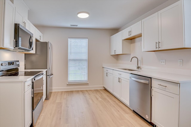 4002 Hidden Haven Ct, Augusta, GA 30909 - kitchen featuring appliances with stainless steel finishes, a sink, light wood finished floors, white cabinets, and light countertops