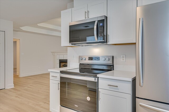 4002 Hidden Haven Ct, Augusta, GA 30909 - kitchen with stainless steel appliances, light countertops, light wood-type flooring, a raised ceiling, and white cabinets