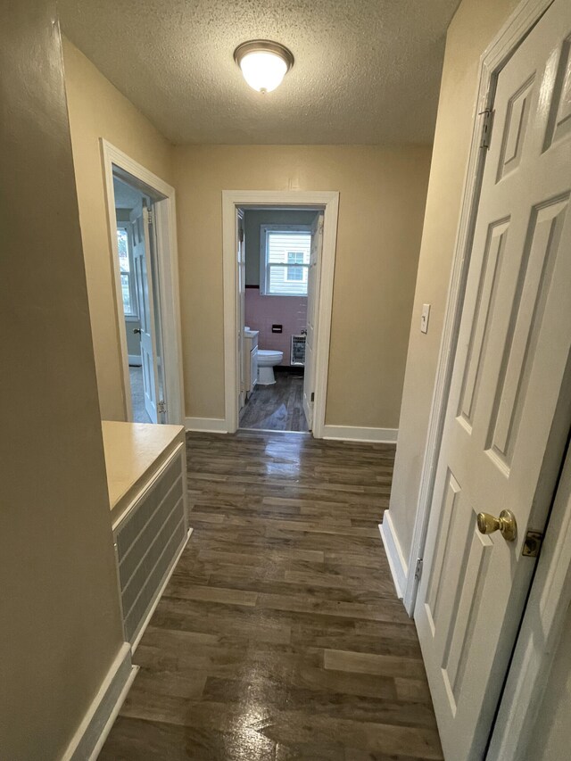 hallway with dark hardwood / wood-style floors and a textured ceiling