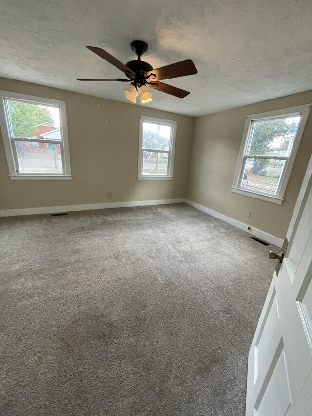 carpeted spare room featuring ceiling fan and a textured ceiling