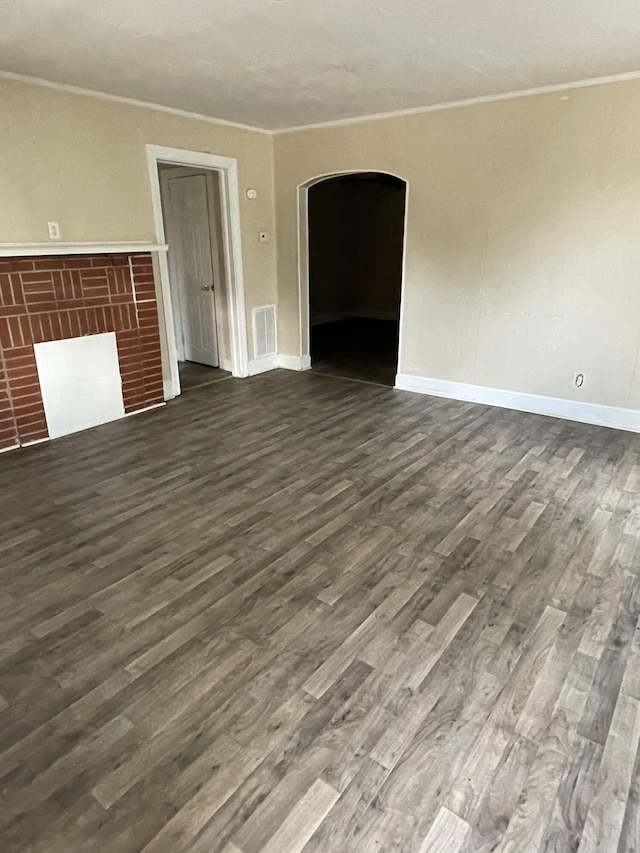 unfurnished living room featuring a fireplace, dark hardwood / wood-style flooring, and ornamental molding