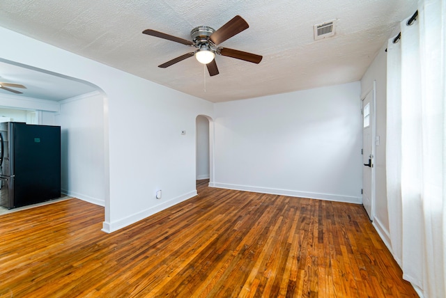 spare room with a textured ceiling, ceiling fan, and dark wood-type flooring