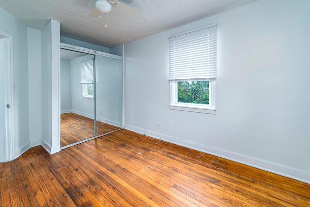 unfurnished bedroom with wood-type flooring, a textured ceiling, a closet, and ceiling fan