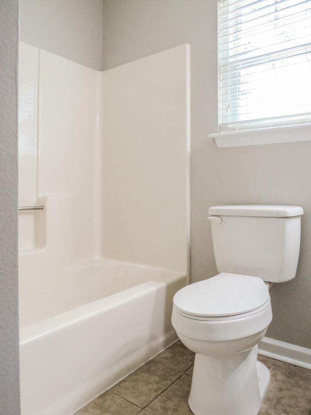 bathroom with bathing tub / shower combination, tile patterned floors, and toilet