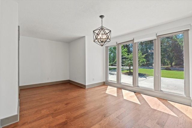 unfurnished dining area with plenty of natural light, wood finished floors, and a textured ceiling