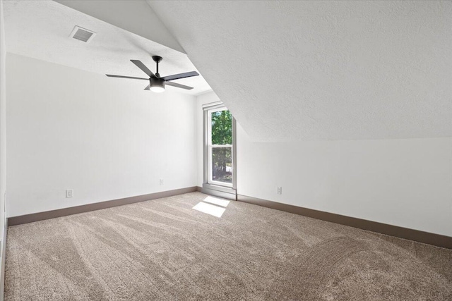 additional living space featuring carpet floors, vaulted ceiling, a textured ceiling, baseboards, and ceiling fan