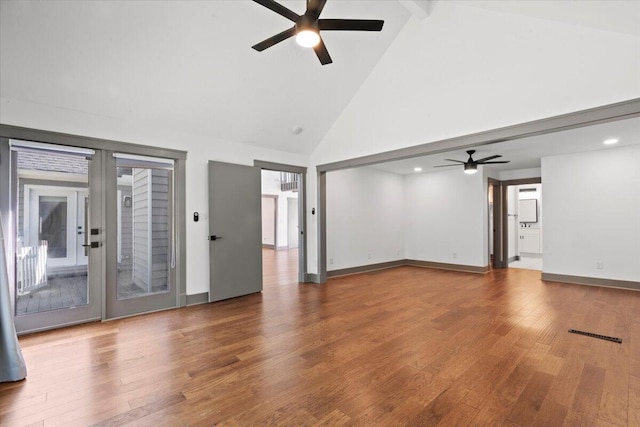 unfurnished living room featuring a ceiling fan, high vaulted ceiling, wood finished floors, beamed ceiling, and baseboards