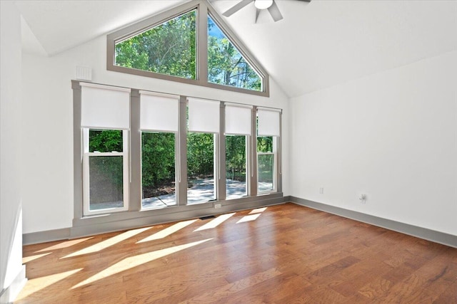 unfurnished room with ceiling fan, high vaulted ceiling, wood finished floors, and baseboards