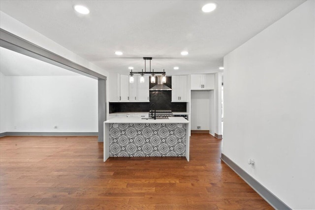 kitchen with wall chimney range hood, light countertops, white cabinets, recessed lighting, and backsplash