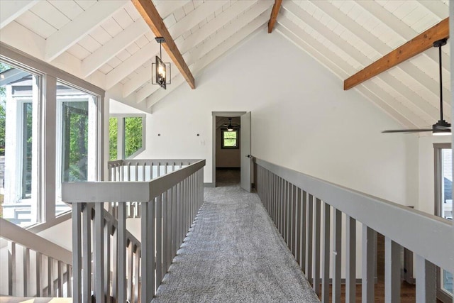 hall featuring beam ceiling, high vaulted ceiling, an upstairs landing, and carpet floors
