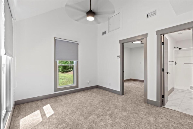 unfurnished bedroom featuring carpet, a towering ceiling, baseboards, and ceiling fan