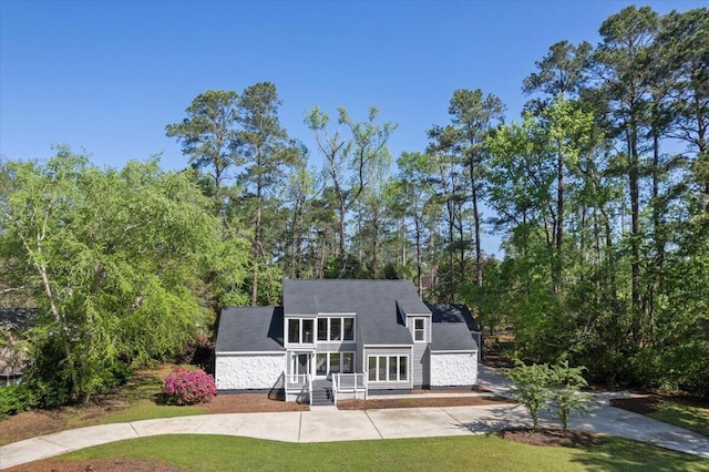 back of property featuring a yard, covered porch, and concrete driveway