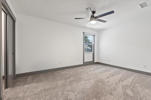 unfurnished bedroom featuring carpet, a textured ceiling, baseboards, a closet, and a ceiling fan
