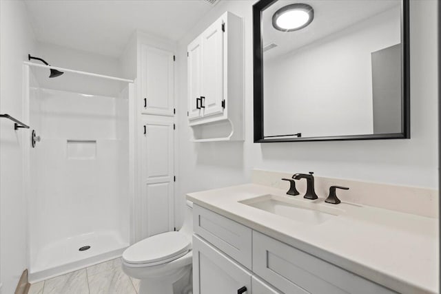bathroom featuring a stall shower, vanity, and toilet