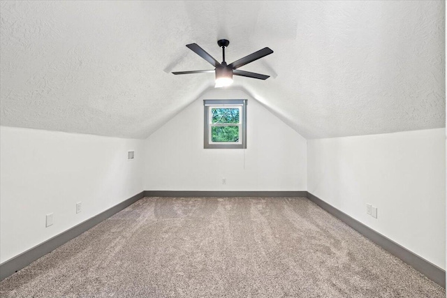 bonus room with carpet floors, ceiling fan, a textured ceiling, baseboards, and lofted ceiling