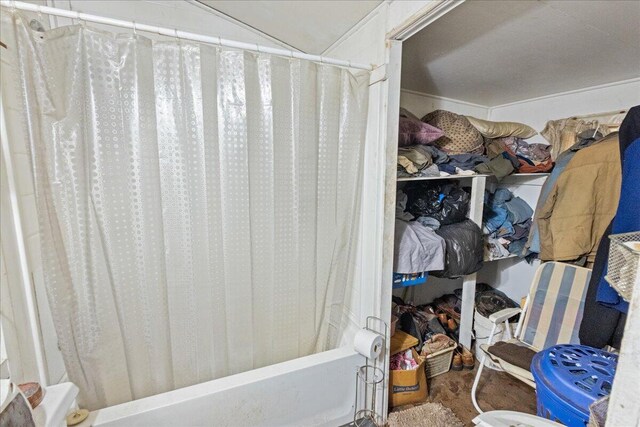 interior space with hardwood / wood-style floors, shower / bath combination with curtain, and lofted ceiling