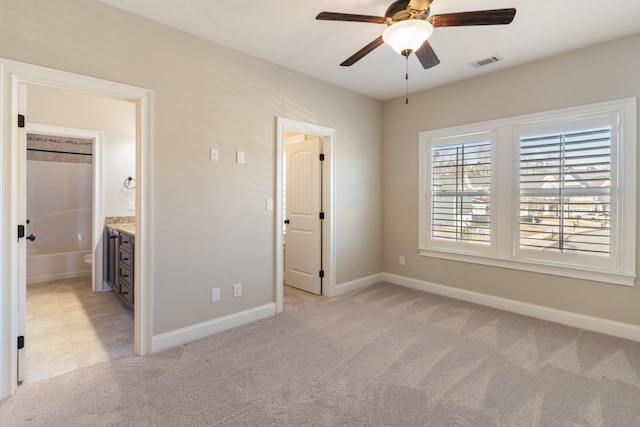 unfurnished bedroom featuring light carpet, connected bathroom, and ceiling fan