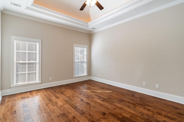 empty room featuring a raised ceiling, hardwood / wood-style flooring, ceiling fan, and ornamental molding