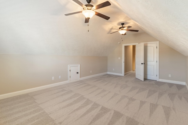 additional living space with ceiling fan, light colored carpet, lofted ceiling, and a textured ceiling