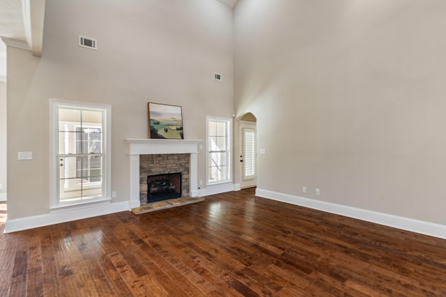 unfurnished living room with a fireplace, a high ceiling, and wood-type flooring