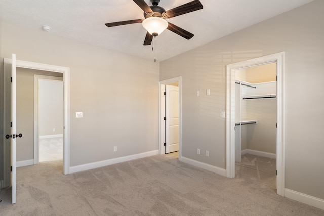 unfurnished bedroom with ceiling fan, light colored carpet, a walk in closet, and a closet