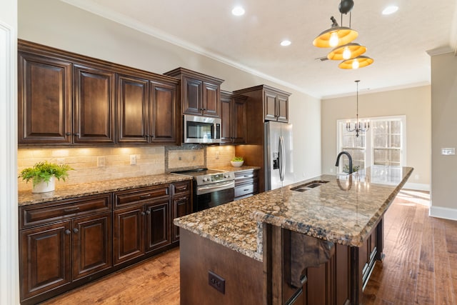 kitchen with sink, pendant lighting, a center island with sink, dark brown cabinets, and appliances with stainless steel finishes