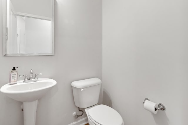bathroom featuring baseboards, a sink, and toilet