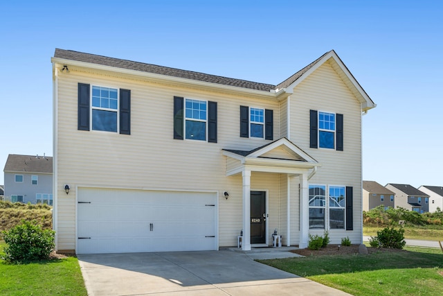 traditional-style house with a garage, a front lawn, and driveway