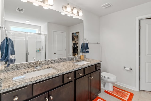 full bath featuring double vanity, a sink, a stall shower, and tile patterned flooring