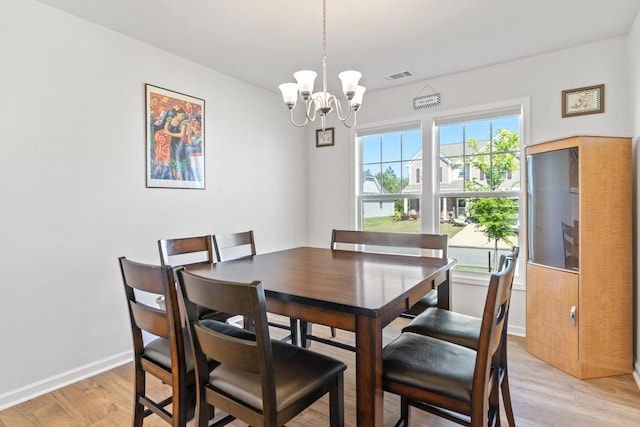 dining room with baseboards, a notable chandelier, light wood-type flooring, and visible vents