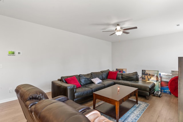 living area with light wood-style floors, baseboards, and a ceiling fan