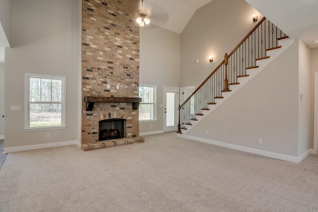 unfurnished living room with ceiling fan, a healthy amount of sunlight, carpet floors, and a brick fireplace