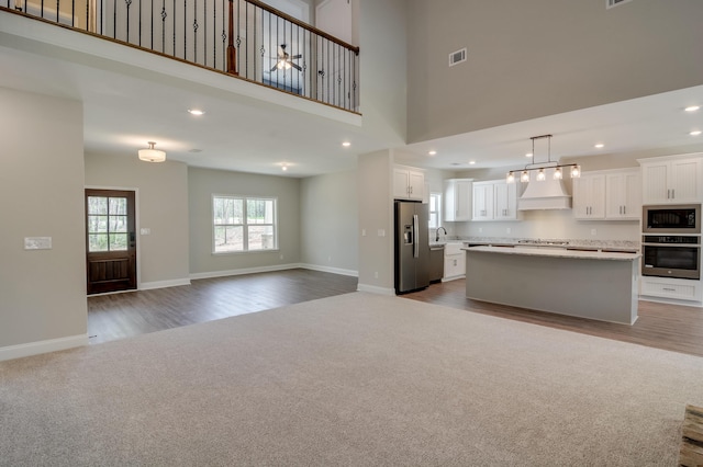 unfurnished living room with a towering ceiling and light carpet